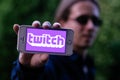 COLOGNE, GERMANY - May 30, 2018: Closeup of serious young man with sunglasses holding white iPhone with TWITCH LOGO on screen Royalty Free Stock Photo